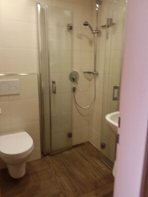 Un bagno con box doccia in vetro, un water e un lavandino.