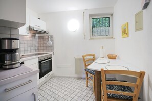 Cuina petita amb fogó, forn i taula de menjador amb cadires.