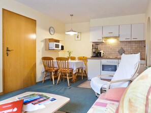 A compact living space with a dining area, kitchenette, and a bed.