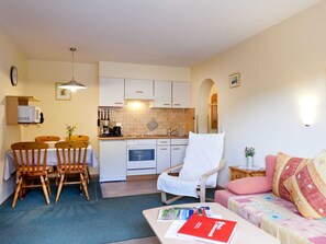 A compact living space with a dining area, kitchenette, and a sofa.