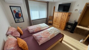 Una habitación con cama, televisión, mueble y silla.