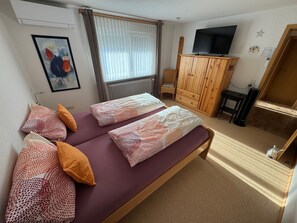 Una habitación con cama, televisión, mueble y silla.