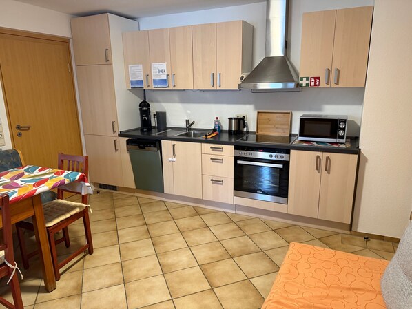A compact kitchen with a dishwasher, stove, microwave, and a small sink.