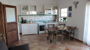 A kitchen with white cabinets, a dining table with chairs, and a wooden door.