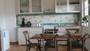 A kitchen with white cabinets, a tiled backsplash, and a dining table with four chairs.