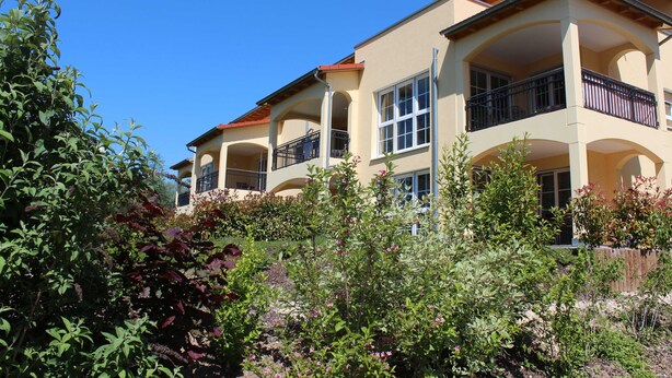 A multi-story building with balconies and large windows.