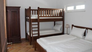 A bunk bed room with a wooden wardrobe and a window.