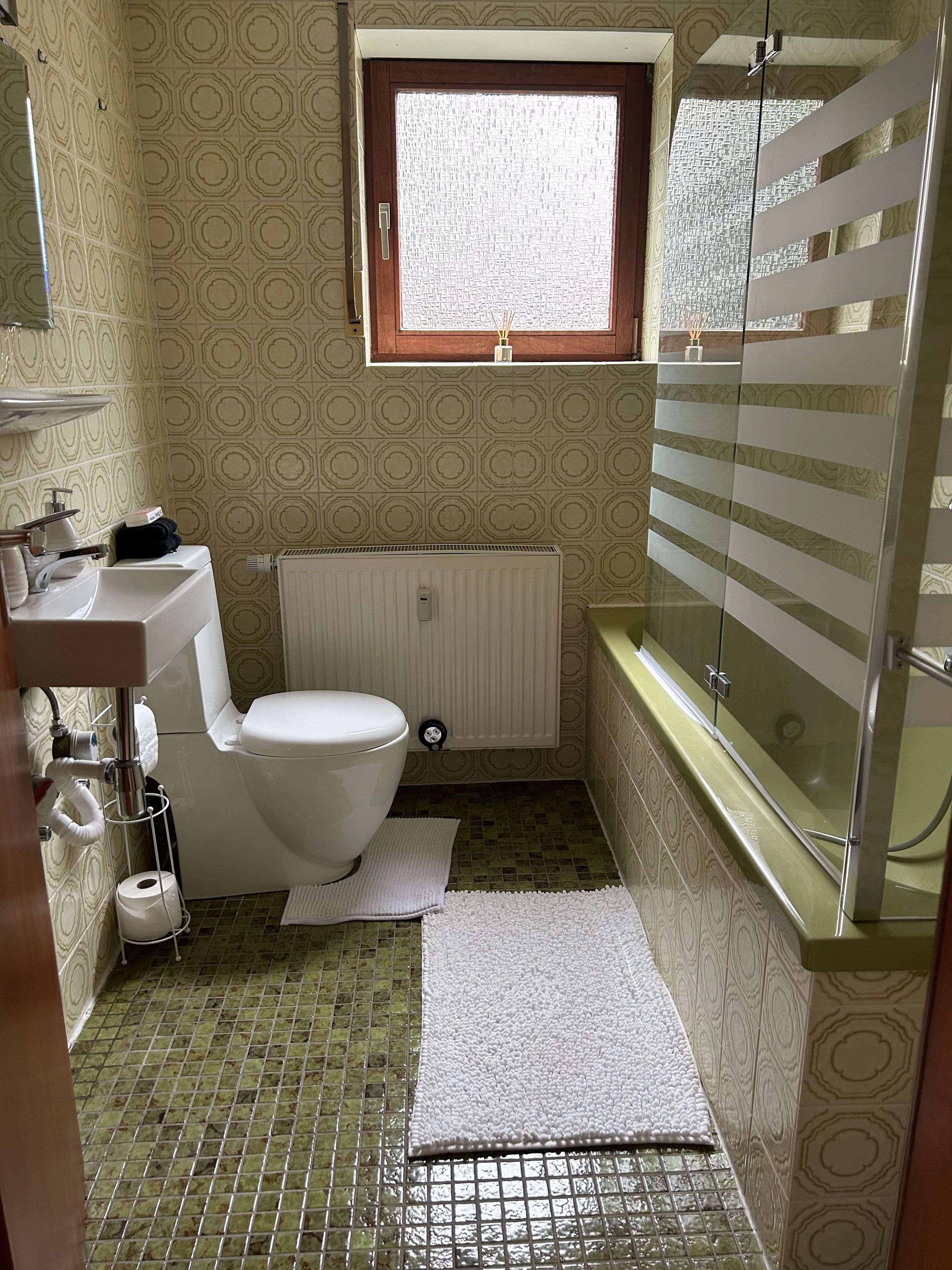 A bathroom with a toilet, sink, window, and bathtub.