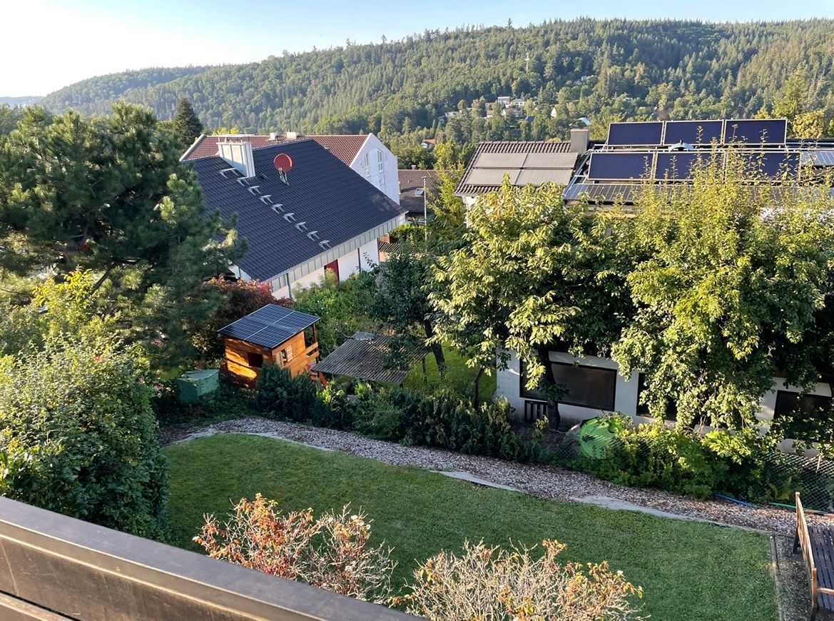 Ein Wohngebiet mit Häusern, Solaranlagen und einer Hügelkette im Hintergrund.