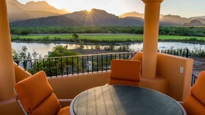 Een balkon met oranje meubilair en uitzicht op een rivier en bergen.