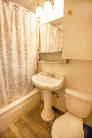 Een bad/douchecombinatie, een haardroger, handdoeken, zeep