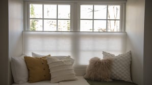 Un dormitorio con cama, almohadas y ventana con persianas.