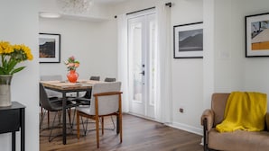 Una sala de estar moderna con comedor, que cuenta con piso de madera, un sofá, una mesa de centro y una mesa de comedor con sillas.