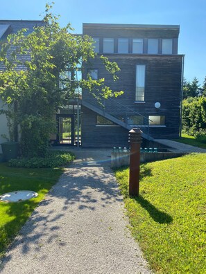 A modern building with a gravel path leading to a glass door entrance.