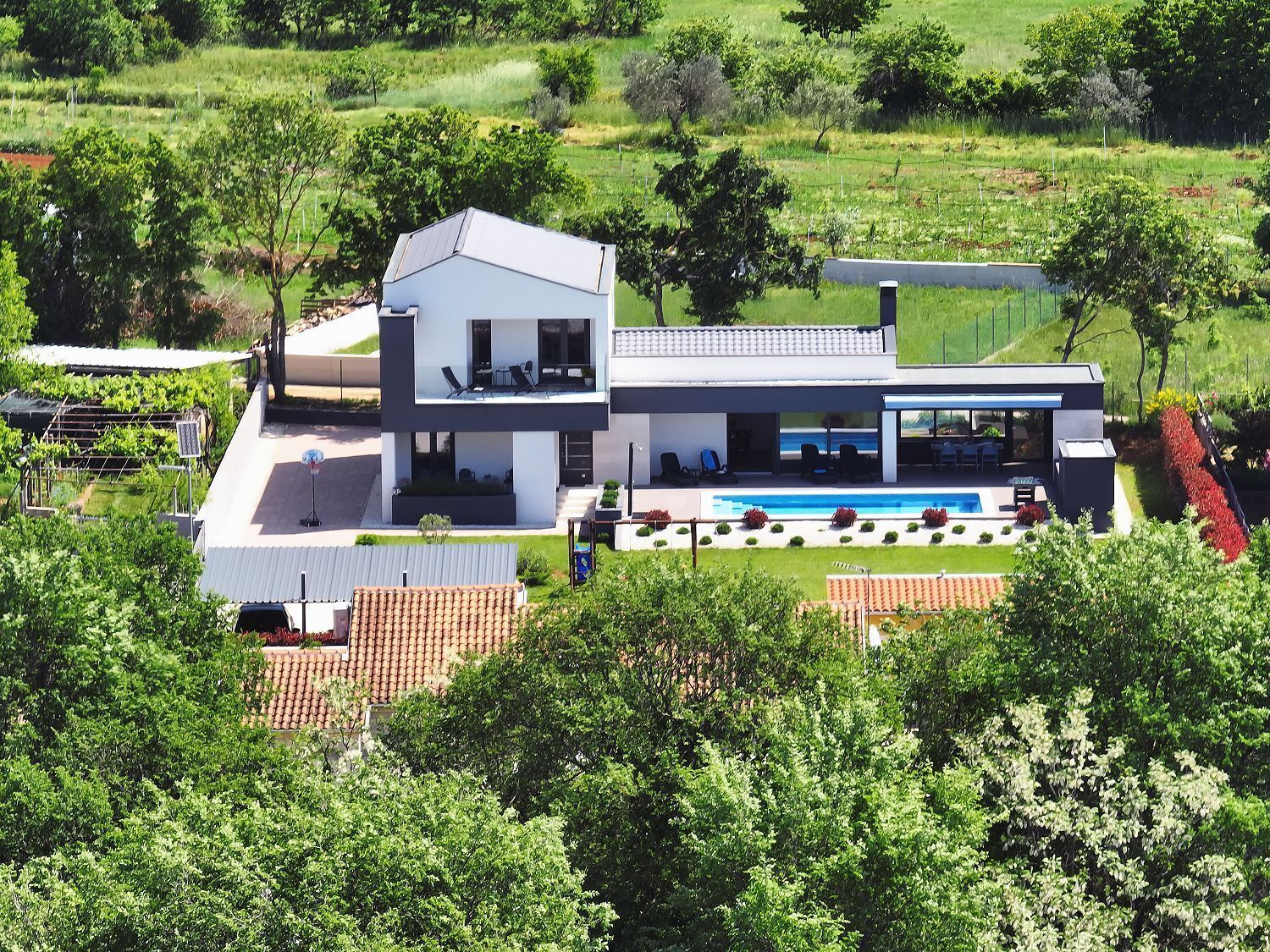 Ein modernes, zweistöckiges Haus mit großer Terrasse und Schwimmbad.