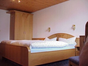 A single bed with a wooden headboard, a wooden wardrobe, and two wall-mounted light fixtures. - Apartment Talblick - Mosertonihof (Elzach)