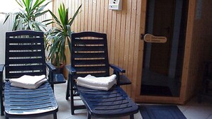 Two lounge chairs with towels, a wooden wall, a door with a sign, and a potted plant.