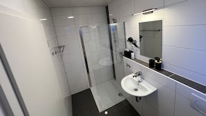 Ein modernes Badezimmer mit Duschkabine aus Glas, Waschbecken und Spiegel.