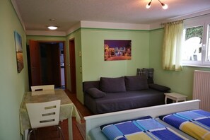 Une pièce comprenant un lit, un canapé, une table à manger avec des chaises, une petite table et un tableau au mur.
