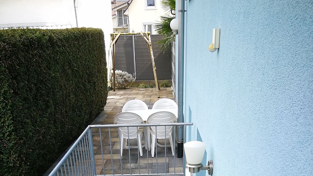 Una escalera lleva a una terraza con mobiliario exterior.