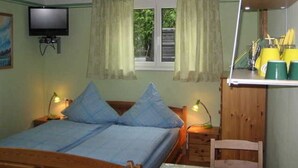 Un dormitorio con una cama, dos lámparas de noche, un televisor y un ventanal con cortinas.