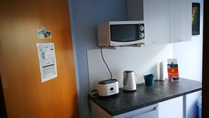 Una kitchenette compacta equipada con microondas, tostadora, hervidor y un refrigerador pequeño.