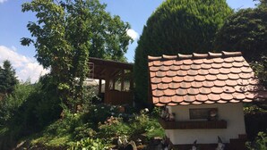 A rustic house with a tiled roof and a garden with gnome statues.