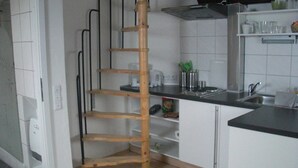 Une cuisine avec des armoires blanches, un comptoir noir et une étagère en bois de style échelle.