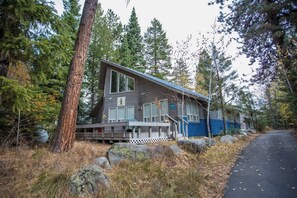 A cabin with a deck, surrounded by trees and rocks.