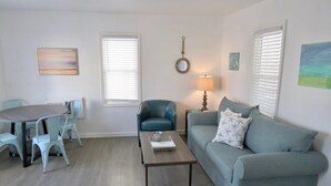 Een zithoek met een ronde tafel, twee stoelen, een bank en een bijzettafeltje.