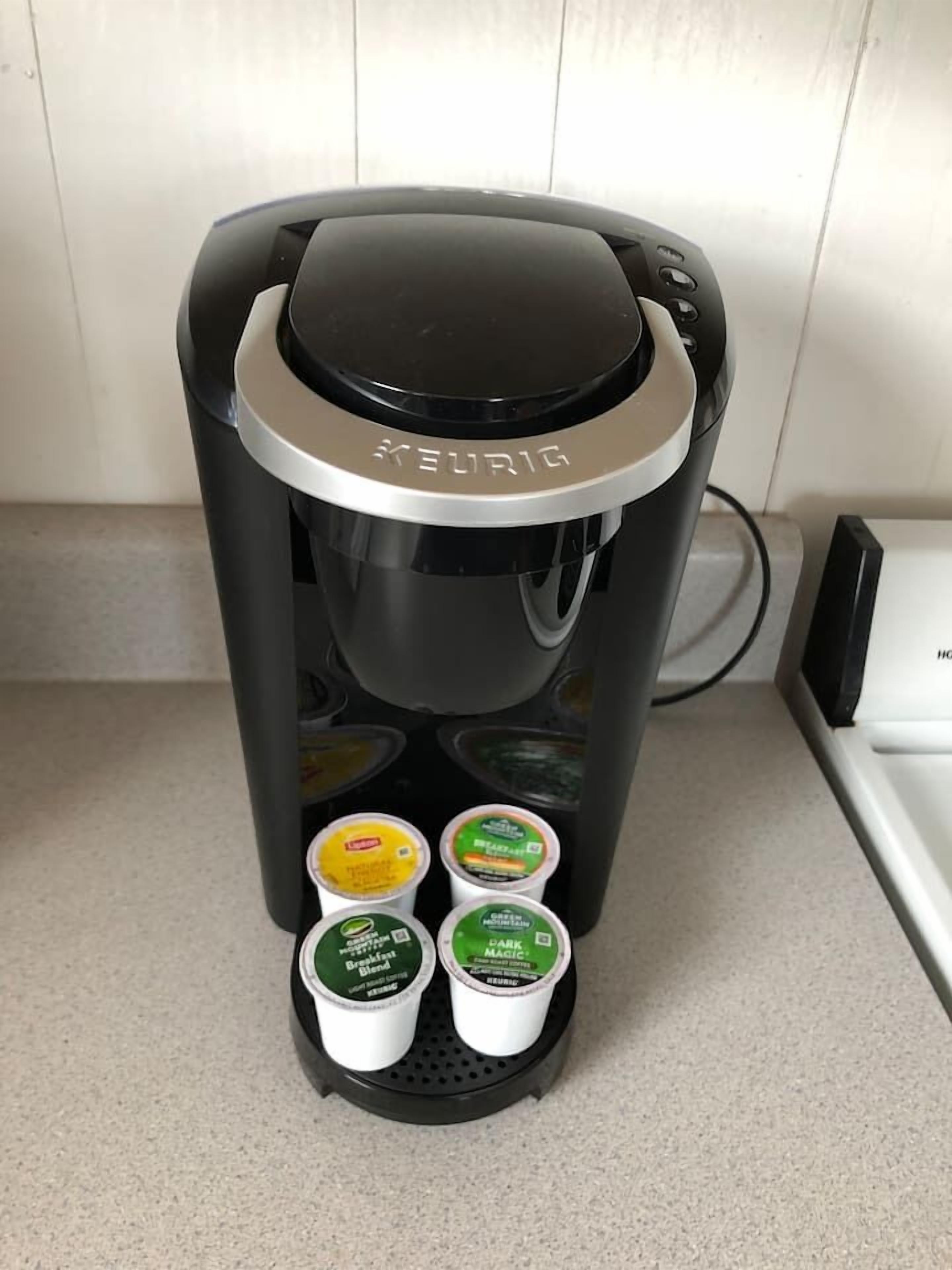 A Keurig coffee maker with four coffee pods on its drip tray.