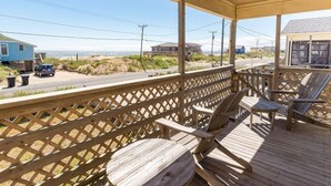 A covered outdoor deck with wooden chairs and a lattice railing. - Saltaire Cottages14: Just Renovated! 4BR Private Beach Access Ocean View Pool! (Kitty Hawk)