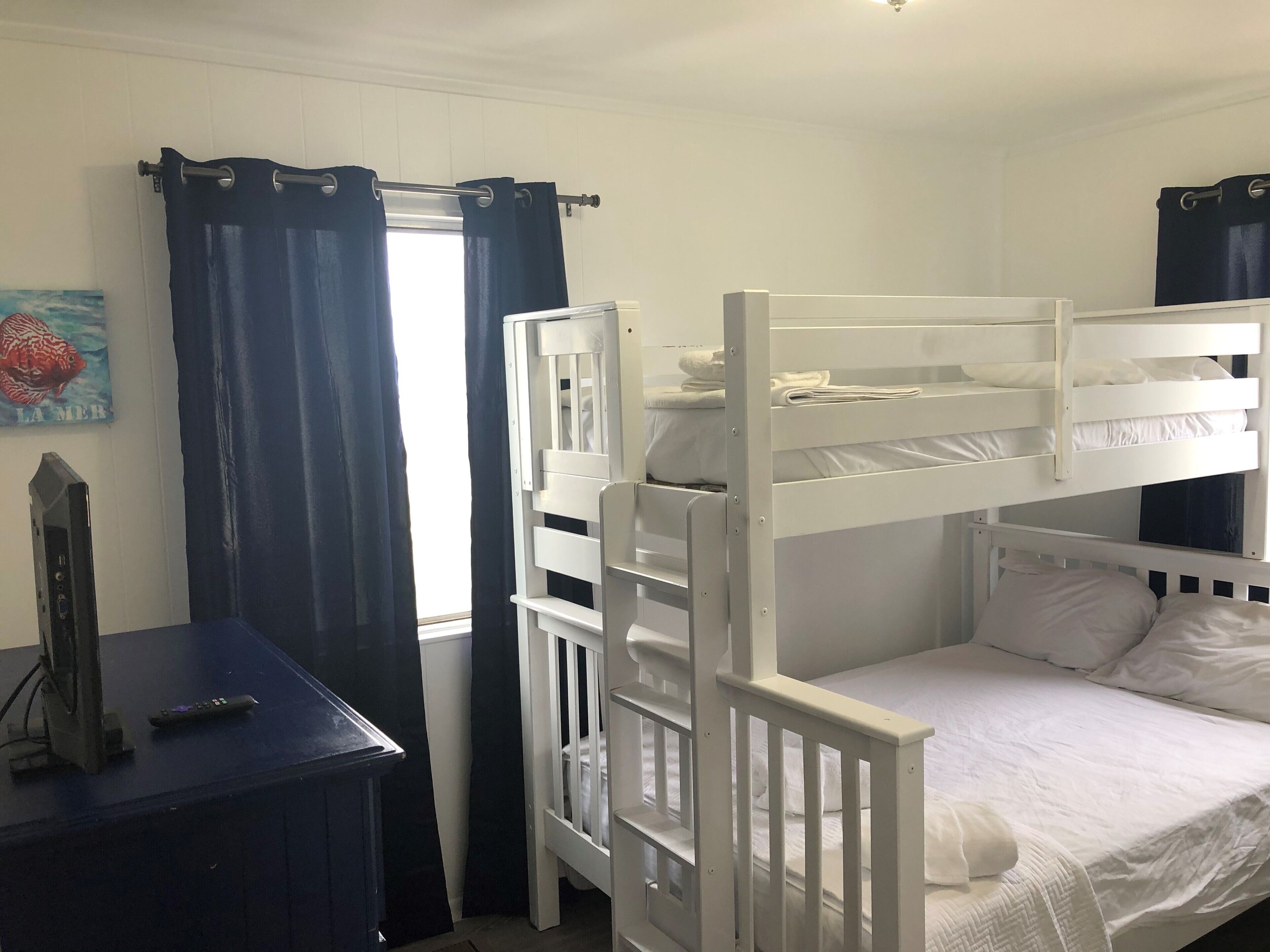 A bunk bed room with a desk and curtains.