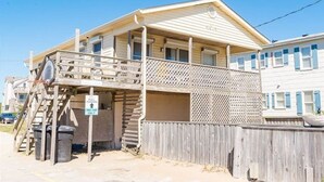 A two-story building with a balcony and a wooden fence. - Saltaire Cottages14: Just Renovated! 4BR Private Beach Access Ocean View Pool! (Kitty Hawk)