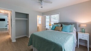 Un dormitorio con cama, mesita de noche y ventilador de techo.