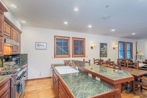 A kitchen with a central island, wooden cabinets, and a dining area with a table and chairs. - Walk to Ski Downtown Telluride Townhome | Guest Favorite! Walk to Gondola & Town (Telluride)