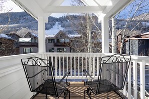 A covered porch with two metal chairs and a table, overlooking a snowy landscape with houses and trees. - Walk to Ski Downtown Telluride Townhome | Guest Favorite! Walk to Gondola & Town (Telluride)