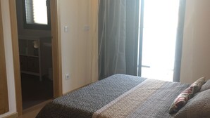 Ein Schlafzimmer mit einem Bett, einem Fenster mit Vorhängen und einer Tür zu einem Badezimmer.