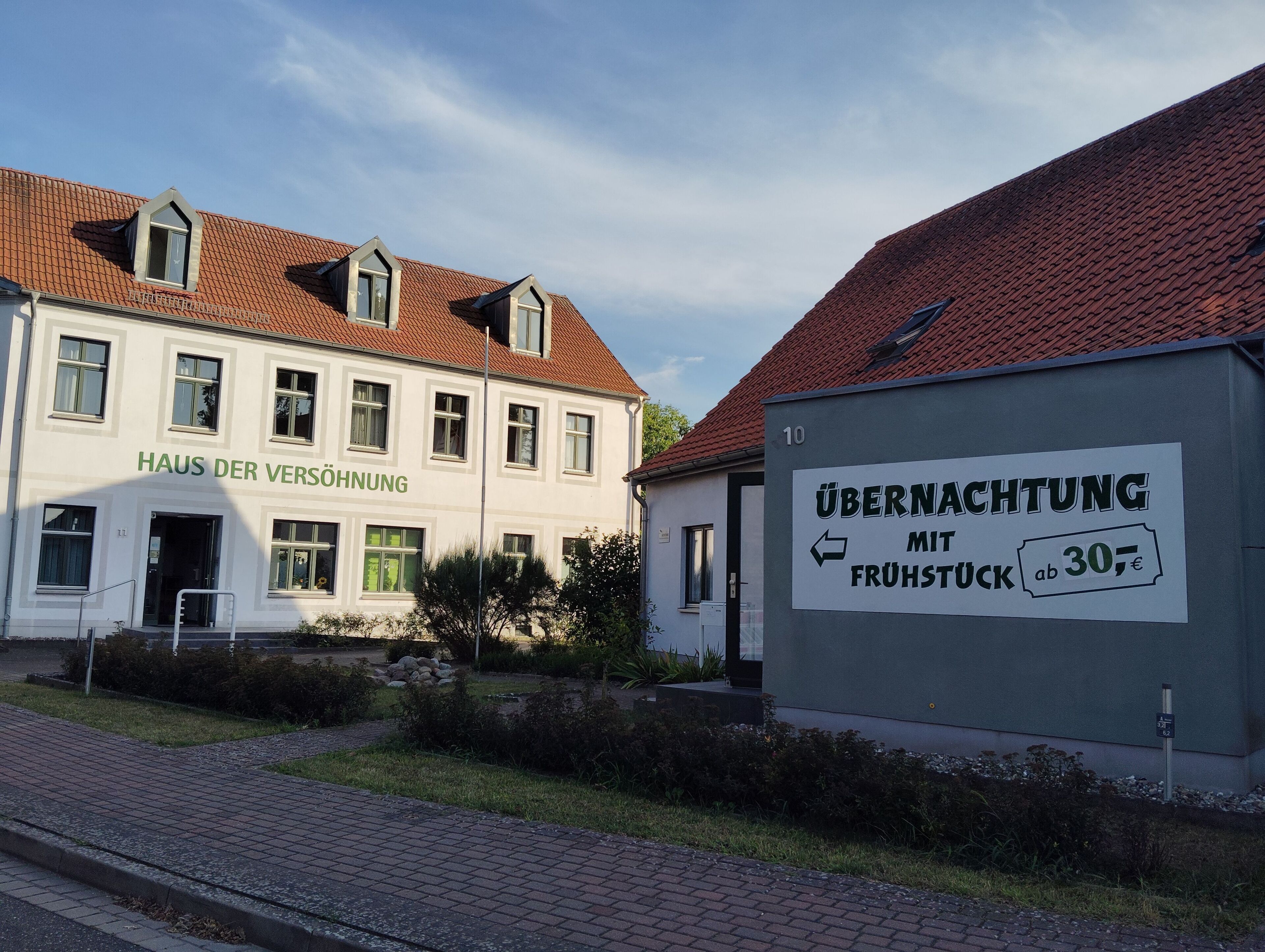 A building with a sign for 'Haus der Versöhnung' and another sign advertising 'Übernachtung mit Frühstück ab 30€'.