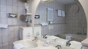 A modern bathroom with two sinks, a large mirror, and a bathtub.