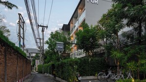 Un bâtiment moderne avec une enseigne indiquant « PARCING », signalant une zone de stationnement. On peut voir des vélos garés à l’extérieur et un chien sur le trottoir.