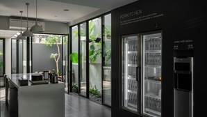 Une cuisine moderne dotée d’un réfrigérateur à porte en verre, d’un point de remplissage de bouteilles d’eau et offrant une vue sur la verdure environnante.