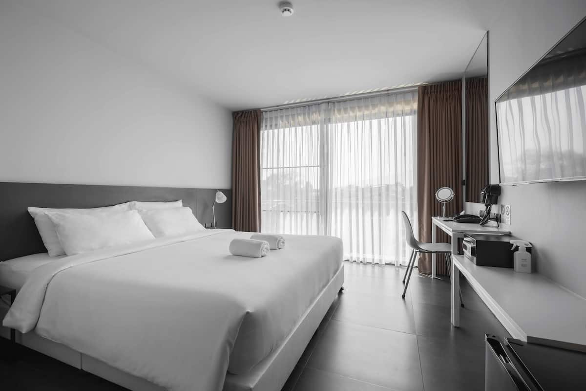 A modern hotel room with a large bed, a desk, and a chair.