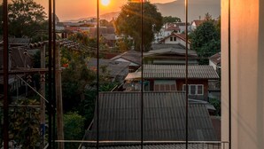 Une vue depuis un balcon donnant sur un quartier résidentiel avec des maisons traditionnelles, au moment du coucher du soleil.