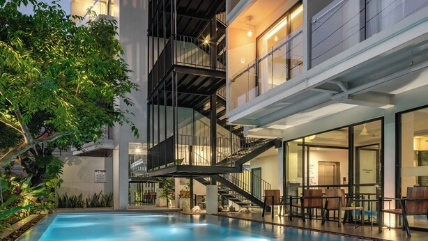 Un hôtel moderne doté d’une piscine, d’un espace extérieur aménagé et d’un escalier menant aux étages supérieurs.