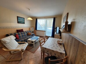 A living room with a sofa, a chair, a table, and a TV. - Apartment 16 - Baltic Sea shell (Zinnowitz)