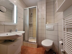 A bathroom with a sink, toilet, shower, and towel rack. - Apartment 16 - Baltic Sea shell (Zinnowitz)
