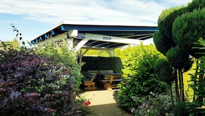 A covered outdoor area with a sign for 'Grill-Roet' and a stack of firewood. - Apartment 16 - Baltic Sea shell (Zinnowitz)