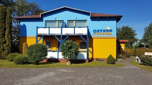 Un bâtiment à la façade bleue et jaune, avec une enseigne indiquant « OSTSEE MUSCHEL », et une entrée pavée.