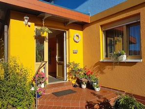 A yellow building with a door, potted plants, and a window. - Apartment 16 - Baltic Sea shell (Zinnowitz)
